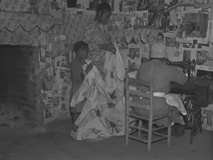 Folk Art Prints: African American mother is assisted by her two daughters as she sews a quilt in their newspapered home on the Pettway