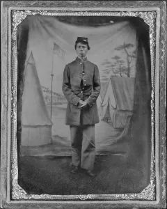 Emancipation Prints: African American soldier posed in front of quaint studio backdrop of tents in a military camp with a prominent U
