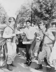 High School Prints: An African American student is escorted to a waiting car by National Guard troops enforcing school integration