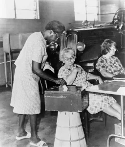 Suffrage Prints: African-American woman placing ballot in box during congressional primary election in Jackson