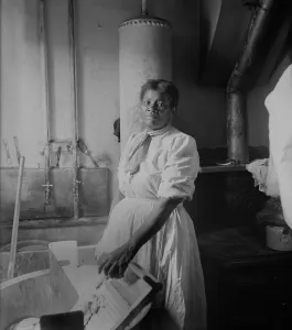Womens Work Prints: African American woman standing by a washtub with her hand on a washboard. Ca. 1920