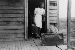 Migration Prints: African American women in a doorway with her luggage