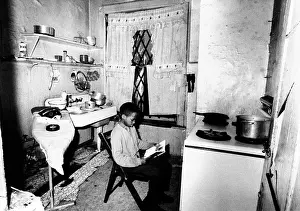 Reading Prints: African American youth studies by the kitchen stove because his apartment