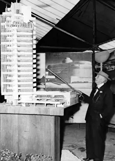Architect Prints: American architect Frank Lloyd Wright pointing to a model of the Price Tower in Oklahoma City