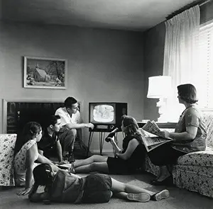 Sofa Prints: American family watching television in the living room of their home