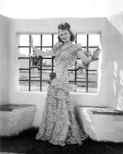 Window Prints: Anna Neagle, modeling a fuschia and white cotton evening gown with blue ribbon bows, 1940
