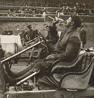 Steering Wheel Prints: Auto racer, Louis Chevrolet in his open-cockpit automobile drinking Coca-Cola