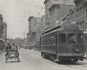 Adults Prints: An automobile shares a street with a trolley car in the business district of Rockford