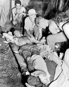 Us Army Prints: Blood Transfusion. A wounded American soldier gets a blood transfusion while assistants hover about the improvised cot