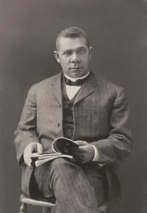 Teacher Prints: Booker T. Washington sits with books on his lap, c. 1903