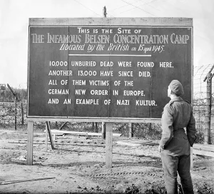 Sign Prints: British soldier stands by a sign posted at the site of the Belsen Concentration Camp, 1945