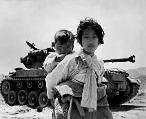 Survival Prints: With her brother on her back, a war weary Korean girl tiredly trudges by a stalled M-26 tank