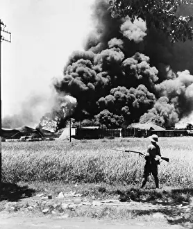 Colonies Prints: Burning oil tanks and cars left by retreating Dutch in Tandjong
