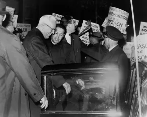 Earl Prints: Chief Justice Earl Warren is escorted through crowd of protestors carrying placards attacking the Supreme Court's