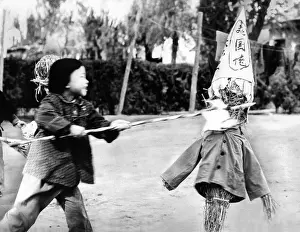 A Chinese kindergarten girl thrusts a spear into a straw effigy labeled with a sign, which roughly translated reads US bad guys