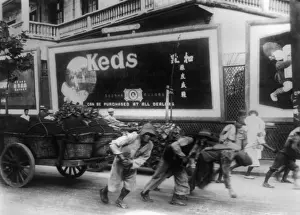Beast Of Burden Prints: Chinese men pulling cart along a city street in China