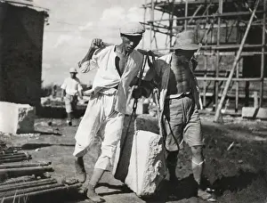 Lcgr1411 Prints: Two Chinese men work together to life a large stone on a construction site