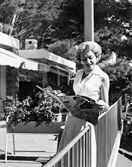 Magazine Prints: Christine Jorgensen, leafing through a film magazine on Capri, Italy, Sept. 22, 1954