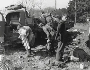 Survival Prints: Civilians loot a knocked out German vehicle loaded with clothing and food
