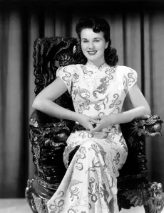 Sitting In Chair Prints: Deanna Durbin posing in costume used in AMAZING MRS. HOLLIDAY, 1943