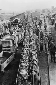 Mining Prints: Dozens of men in open railroad cars on their way into the underground mines in Idaho in 1909
