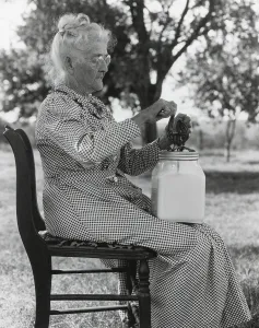 Oklahoma Prints: Elderly farm woman using a small glass butter churn