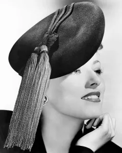 Eleanor Prints: Eleanor Parker, modeling a black felt beret topped with bright red tassels, October 1943
