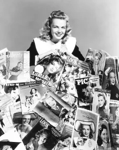 Knox Prints: Elyse Knox posing amid all of the magazines which feature her picture on the cover, 1943