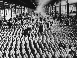 Explosives Prints: English women and men working in storage shed for large shells of a munitions factory