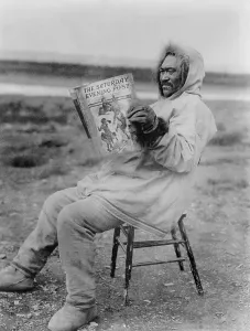 Books Prints: Eskimo man reading Saturday Evening Post in the Arctic region