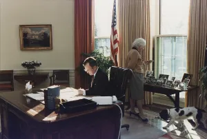 Desks Prints: During his first week as president George Bush works in the Oval Office as wife Barbara looks at photographs behind