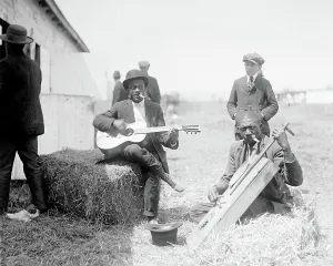 Negro Prints: Folk Music. Two musicians sitting on bales of hay and playing instruments outside a barn