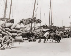 Wharves Prints: Gang of five Chinese dock workers lean hard on ropes to haul a heavy wagon load of sacks on the Hong Kong waterfront