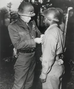 Gen. George Patton, pins the Silver Star on Private Ernest A. Jenkins