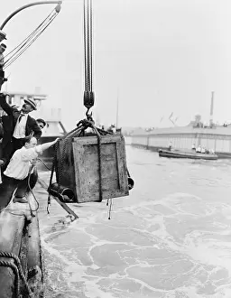 Houdini Prints: Harry Houdini (1874-1926) in the crate being lowered from ship into water in New York harbor
