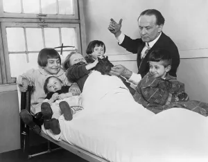 Illusionists Prints: Harry Houdini and his rabbit entertain five hospitalized children. Ca. 1925