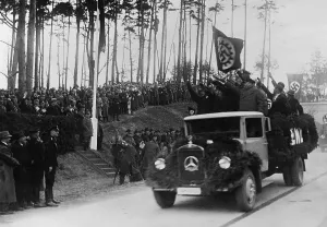 Herman Prints: Hermann Goring in group at left receives the Nazi salute from men riding in a decorated Mercedes truck during inaugural