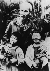 Revolutionaries Prints: Ho Chi Minh (1890-1969), North Vietnamese leader revolutionary with his arms on the shoulders of two young girls