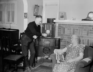 Newspapers Prints: A husband tunes the radio while his wife holds populist right-wing radio priest