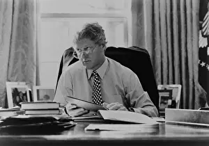 Papers Prints: Informal portrait of President Bill Clinton at his desk in the Oval Office