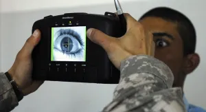 Electronics Prints: An Iraqi police recruit holds his eye open for a retinal scan administered by a US Soldier in Mahmudiyah Iraq May 30