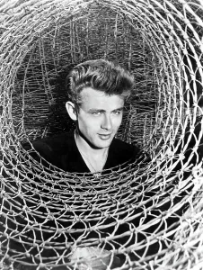 Dean Prints: JAMES DEAN peeking through a spiral of chicken wire, c. mid-1950s