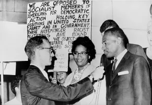April Prints: James Meredith and wife in front of segregationist poster as they talk to a reporter