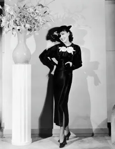 Parker Prints: Jean Parker, modeling a collegienne frock of black satin with a split skirt and white satin flowers