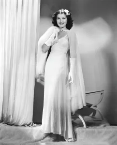 Parker Prints: Jean Parker, modeling a white chiffon evening gown with a rhinestone-buckled cape and white fox throw