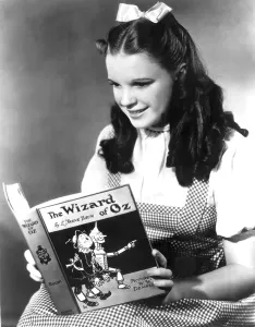2001 Prints: JUDY GARLAND, dressed as Dorothy reading The Wizard of Oz
