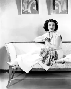 1930s Fashion Prints: Kay Francis, modeling white crepe lounging pajamas with a paisley sash, ca. mid-1930s