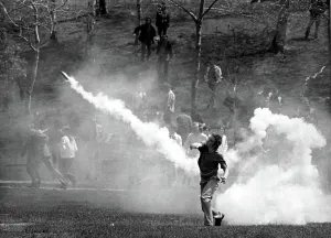 1999 Prints: KENT STATE UNIVERSITY, student tosses a tear-gas bomb back at the National Guard who fired it to disperse the crowd