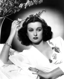 Trending: SHE KNEW ALL THE ANSWERS, Joan Bennett, reclining and touching a flower, 1941