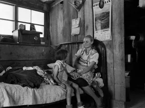Parents Prints: Listening to the radio. A mother smiles at her daughter as they listen to the radio in their dugout home